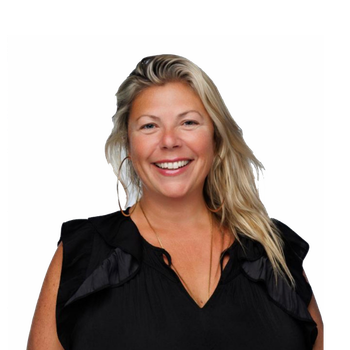 Smiling woman with long blonde hair wearing a sleeveless black top, standing against a plain white background.