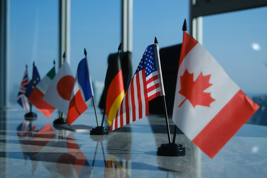 Small desk flags of several countries, including Canada, the United States, Germany, France, Italy, Japan, and the United Kingdom, displayed on a conference table.